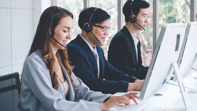 IT support specialists assisting clients at their workstations